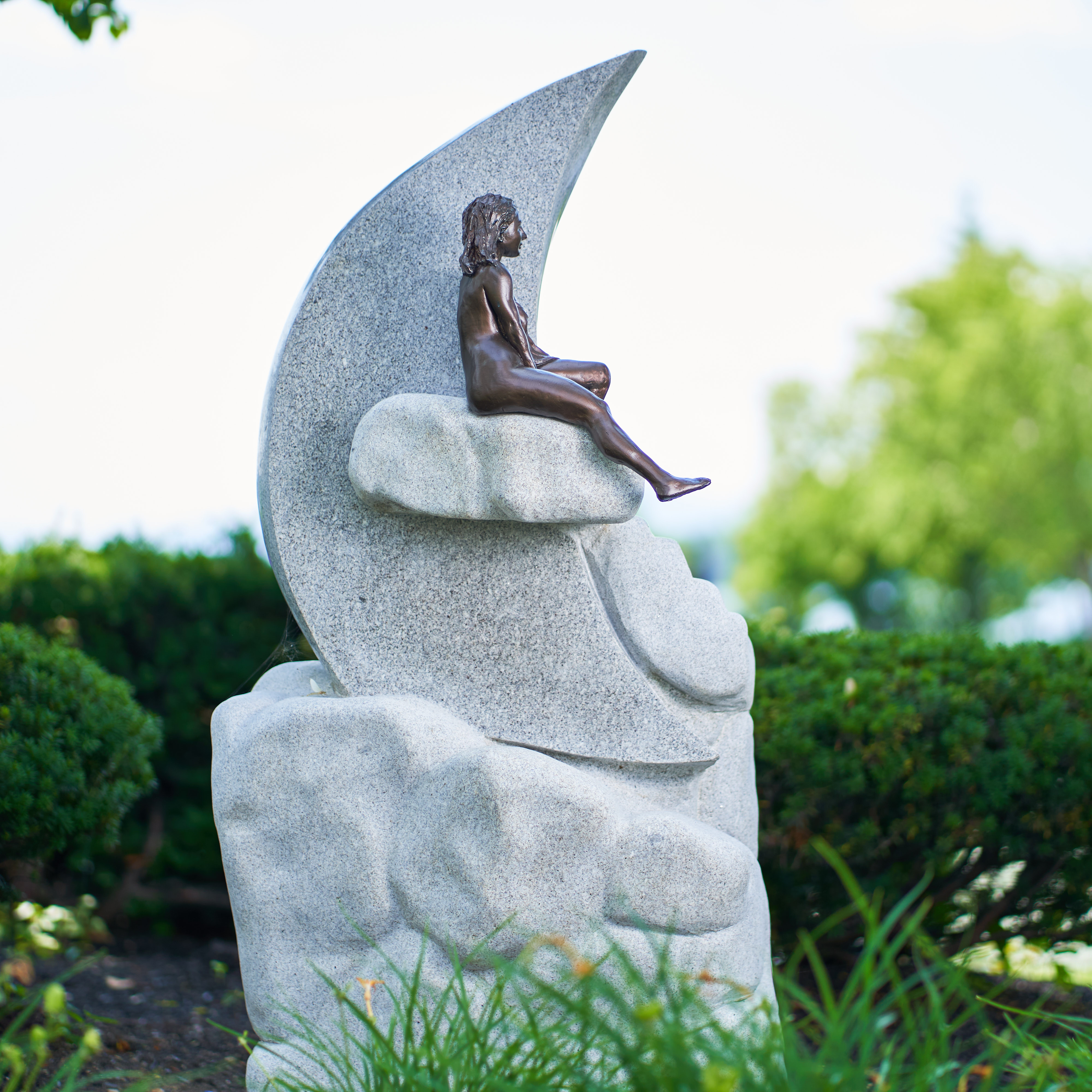 Sculpture of a nude woman sitting on a cloud bisecting a crescent moon. Granite, woman is cast resin.
