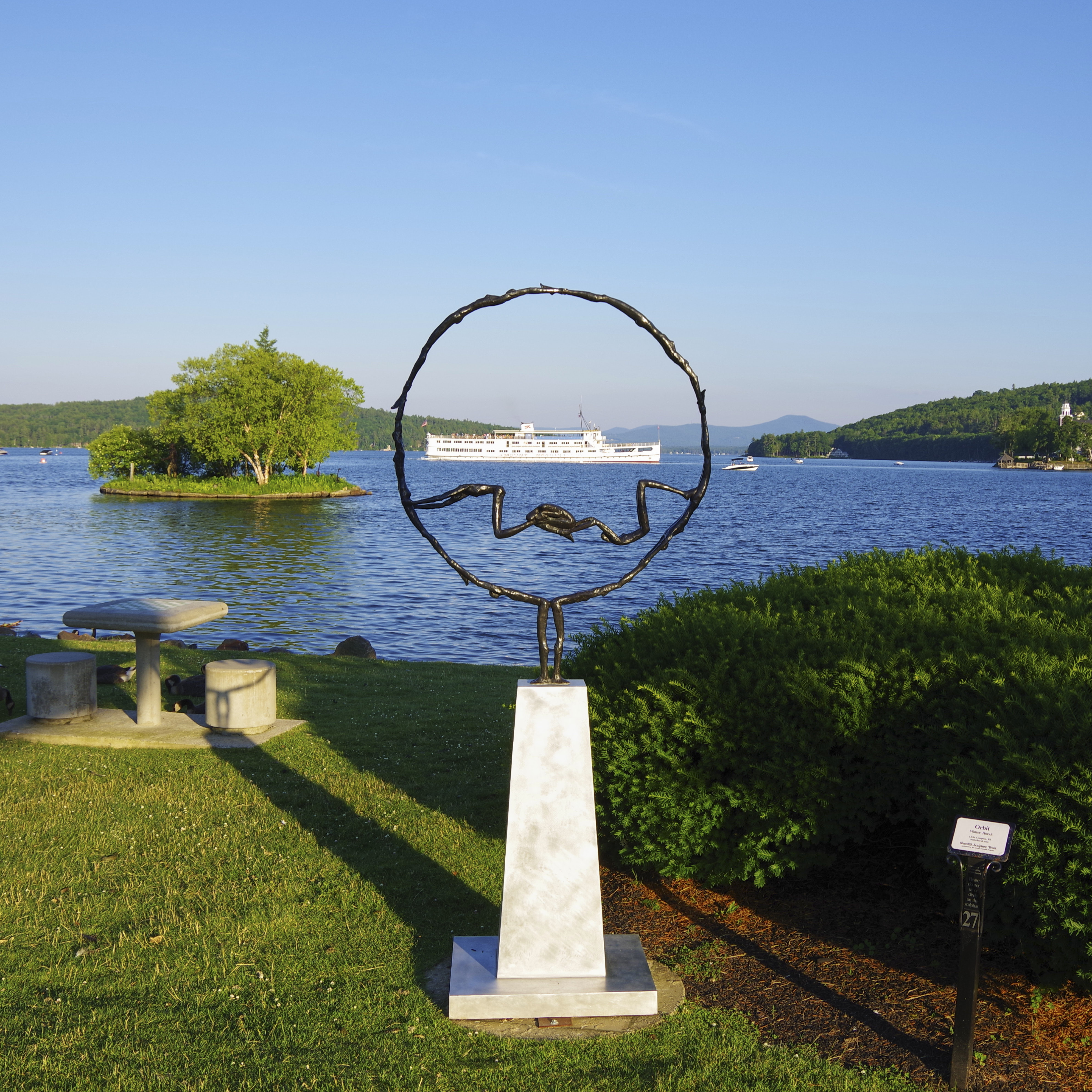 Abstract sculpture positioned in front of a lake. The Mount Washington boat is visible in the water.