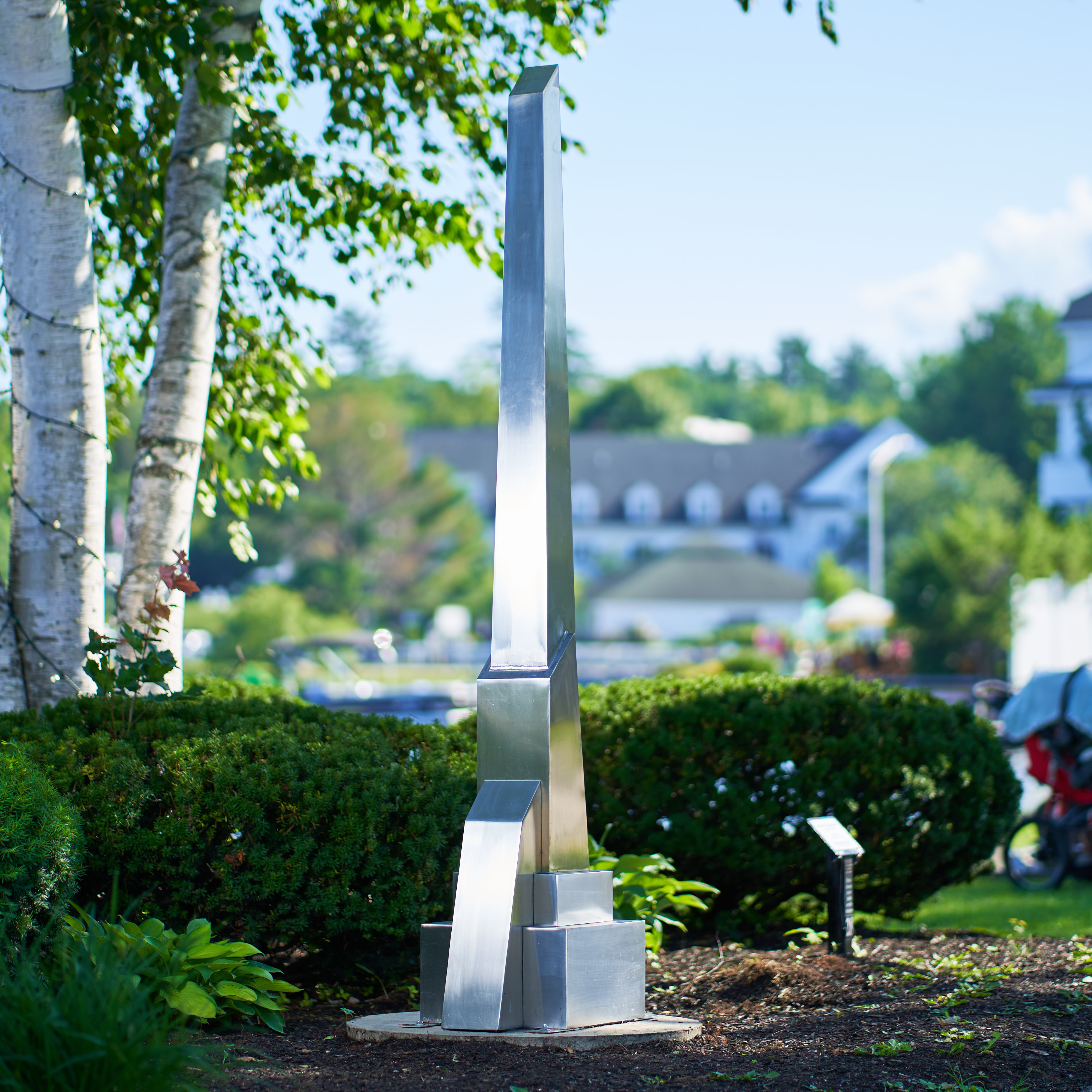 Sculpture of the negative space around an abstract human form. It is bright red with gold along the edge of the center void. Painted urethane and gold leaf.