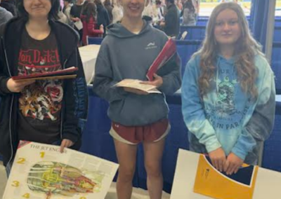 Three ILMHS students holding posters and papers
